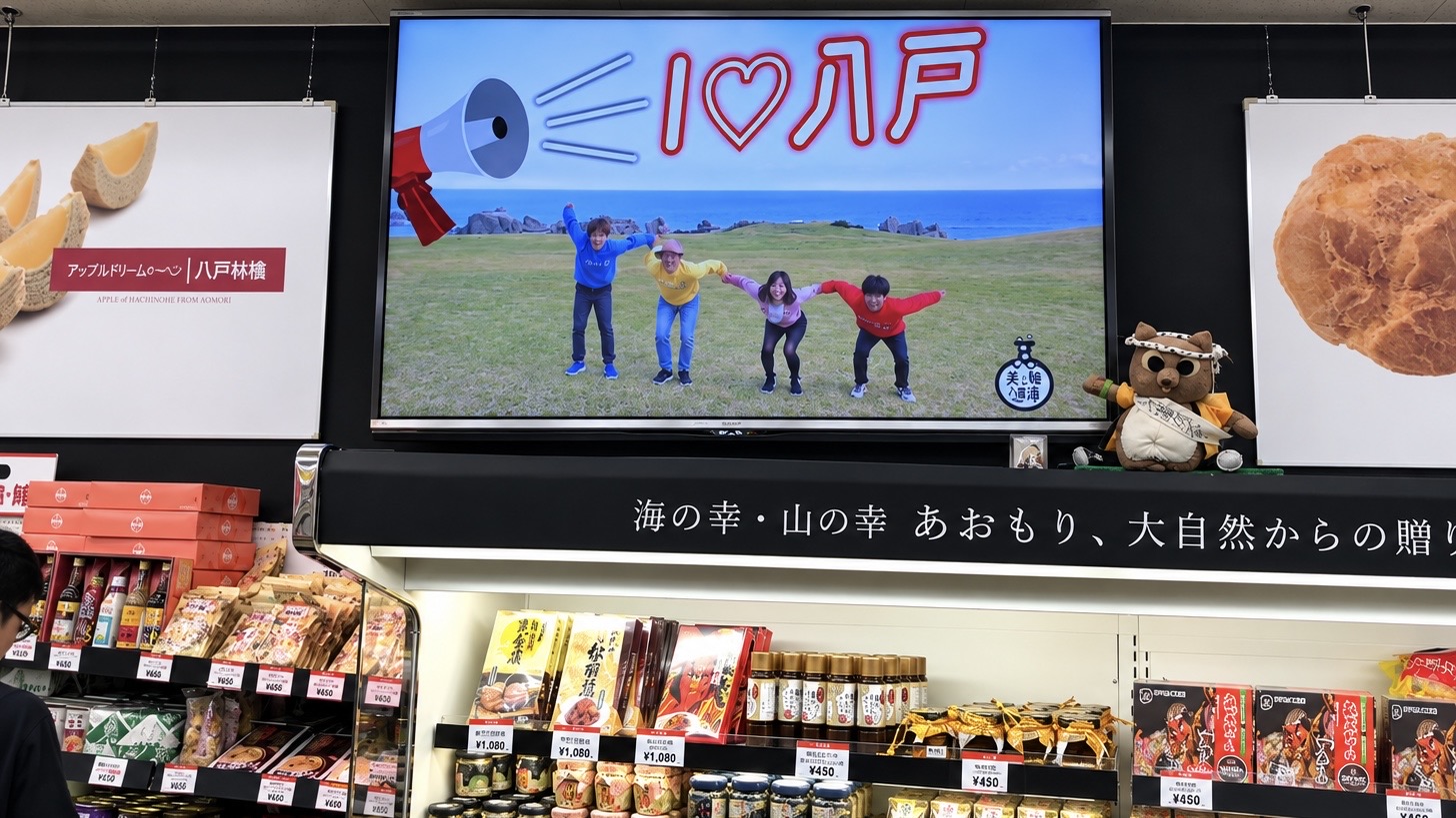 八食センターの売り場の大型モニターに映る「おんでやんせ八戸」