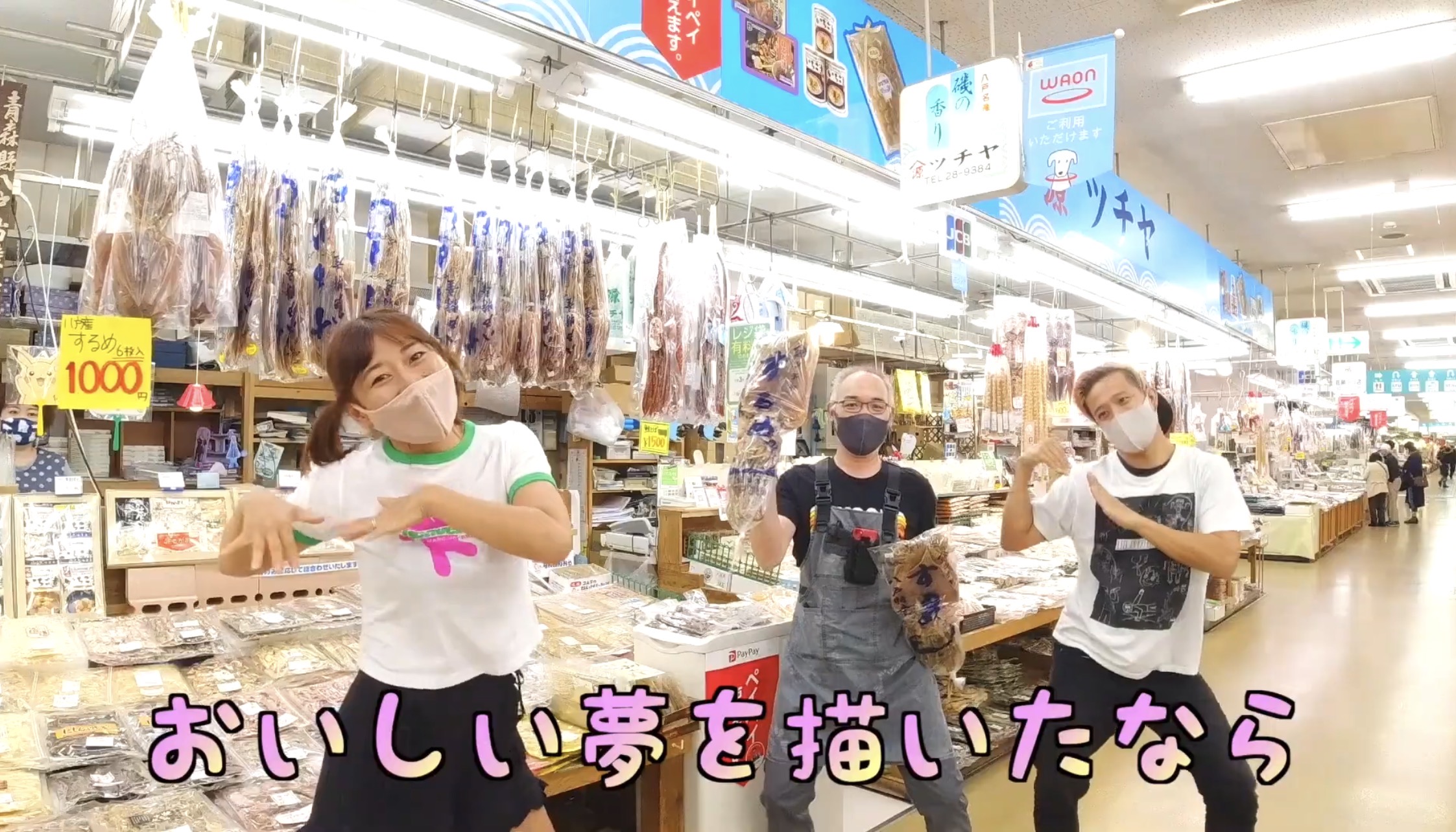 干物が並ぶツチヤの売り場で店員さんがイカの干物を手に踊る様子